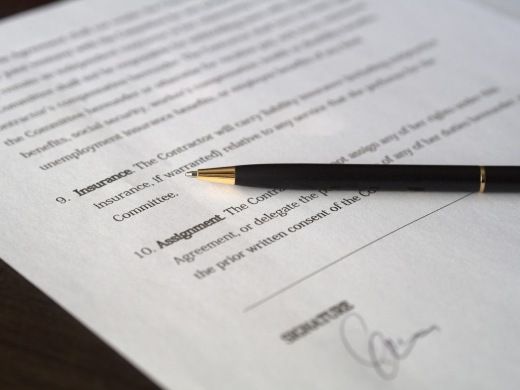 Document on table with signature line and a pen at the ready.